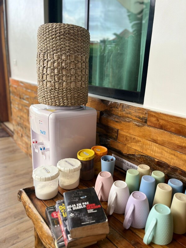 Una cocina con cafetera, recipientes de almacenamiento y una pila de libros.