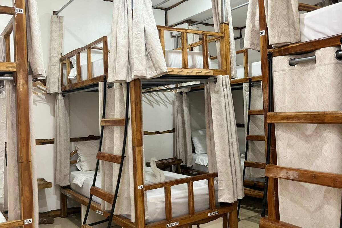 Bunk beds with wooden frames and white bedding, arranged in a dormitory-style room.