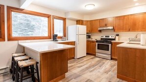 A modern kitchen with wooden cabinets, a central island, and a large window. - 3-Bedroom Meadow Creek Townhom 3 Townhouse (Vail)