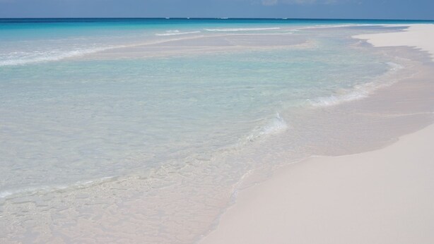Una playa con agua turquesa cristalina y arena blanca.