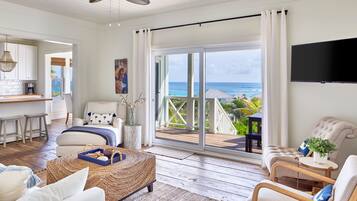 A spacious living area with a large sliding glass door leading to a balcony with a view of the ocean.