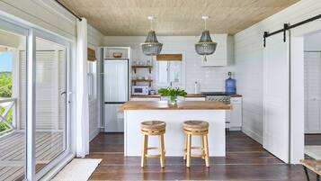 A kitchen with a wooden island, two barstools, a microwave, and a water dispenser.
