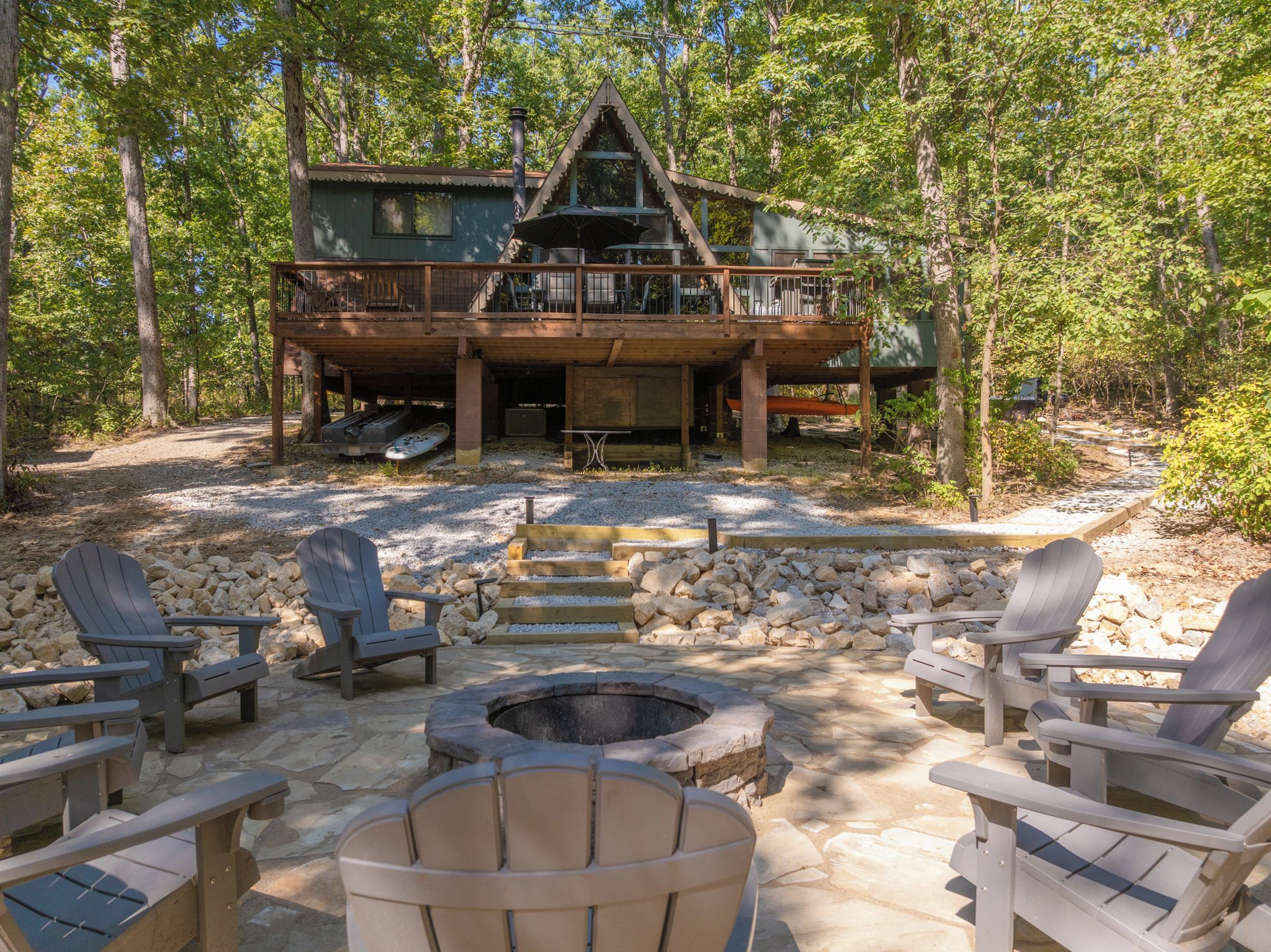 A cabin with a deck, outdoor seating, and a fire pit.