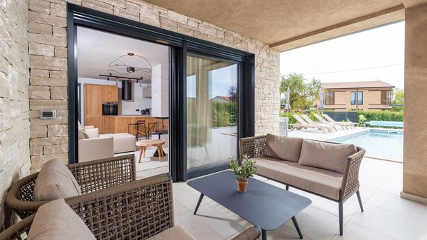 A modern outdoor living space with a pool, wicker furniture, and a view of a residential area. - Charming Villa Vallis with swimming pool, jacuzzi and sauna (Kadumi)