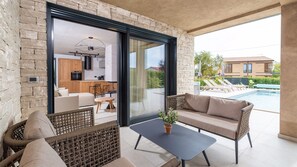 Un espace de vie extérieur moderne, doté d'une piscine, de meubles en osier et offrant une vue sur un quartier résidentiel.