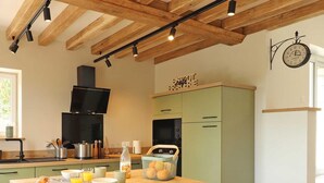 Una cocina moderna con una isla central, vigas de madera en el techo y un reloj en la pared.