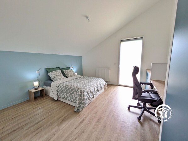 A bedroom with a bed, bedside table, lamp, and a chair.