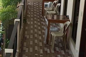 A corridor with a patterned floor, white plastic chairs, and a wooden table. - Alona KatChaJo Inn (Panglao Municipality)