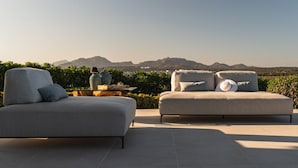 A modern outdoor seating area with two sofas and a table, set against a backdrop of mountains and greenery. - Villa Blue Sphere by Wonderful Italy (Olbia)
