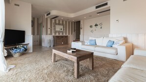 A spacious living room with a large flat-screen TV, a wooden coffee table, a white sofa, and a patterned wall. - Villa Blue Sphere by Wonderful Italy (Olbia)