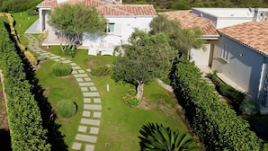 A villa with a tiled roof, surrounded by a well-maintained garden and a view of the sea. - Villa Blue Sphere by Wonderful Italy (Olbia)