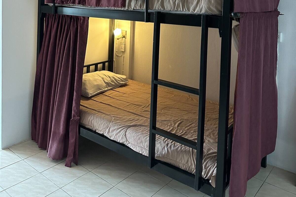 A bunk bed with a headboard and a lower bed, both with pillows and a blanket.
