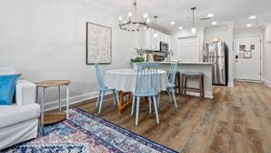 Una cucina moderna con mobili bianchi, un frigorifero in acciaio inossidabile e un'area pranzo con un tavolo rotondo e sedie blu.