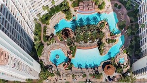 Une vue aérienne d’un complexe hôtelier doté de plusieurs piscines, d’une plage et d’immeubles de grande hauteur.