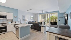 Une cuisine moderne avec des meubles blancs, un îlot central et un coin repas doté d’une table en bois.