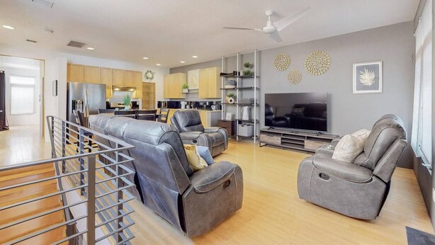 Una sala de estar moderna con un conjunto de sofás, un televisor y una zona de cocina.