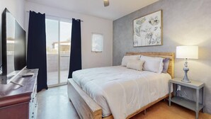 Un dormitorio con cama, televisión, ventilador de techo y un cuadro en la pared.