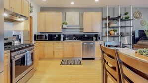 Una cocina moderna con armarios de madera, electrodomésticos de acero inoxidable y una isla central con asientos.