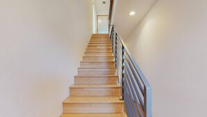 Una escalera de madera con barandilla de metal que sube a un piso superior.