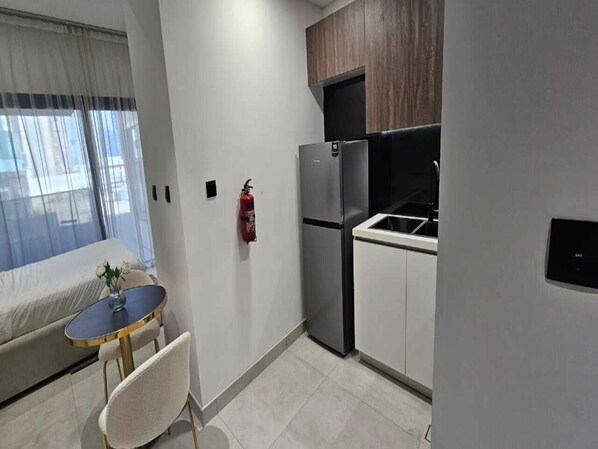 A compact kitchen with a refrigerator, stove, and a small dining table with chairs.