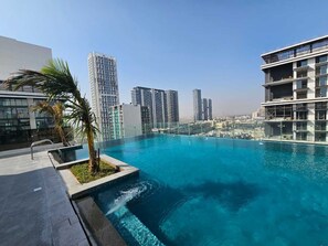A rooftop infinity pool with a city view, surrounded by modern buildings.