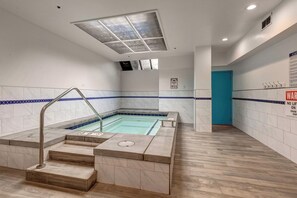 Ein Schwimmbecken mit Stufen und einer blauen Tür, sowie ein Schild mit einem Notruf-Telefon für 911.