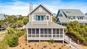 A two-story house with a balcony and a covered porch. - "Bleu Fin Cottage" BHI Club, Ocean Front, Steps to Beach, Sleeps 6 (Bald Head Island)