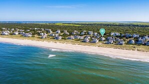 An aerial view of a coastal residential area with houses along the beach and a clear view of the ocean. - "Bleu Fin Cottage" BHI Club, Ocean Front, Steps to Beach, Sleeps 6 (Bald Head Island)