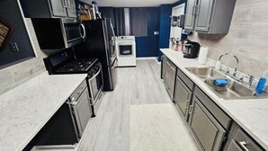 A compact kitchen with a built-in oven, microwave, and sink. - City Living—sleeps 12 
15-20 mins from Acrisure Stadium, PNC Park, Mt Washington (Pittsburgh)