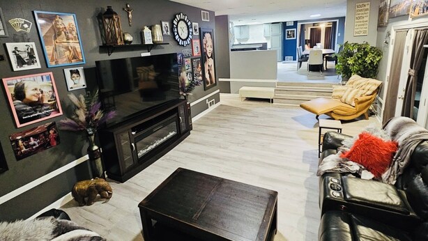 A modern living room with a flat-screen TV, a fireplace, and a dining area with a yellow chair. - City Living—sleeps 12 
15-20 mins from Acrisure Stadium, PNC Park, Mt Washington (Pittsburgh)