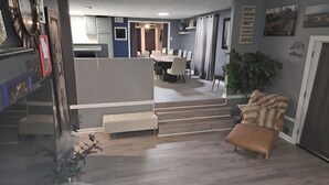 A modern living room with a sofa, a dining area with a table and chairs, a staircase, and a large potted plant. - City Living—sleeps 12 
15-20 mins from Acrisure Stadium, PNC Park, Mt Washington (Pittsburgh)