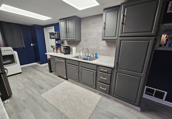 Una cocina moderna con armarios grises, encimera blanca y alfombra gris.