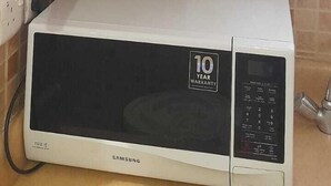 A kitchen with a microwave, a cabinet with dishes, and a sign listing available services. - luluh elthurayaa (Riyadh)