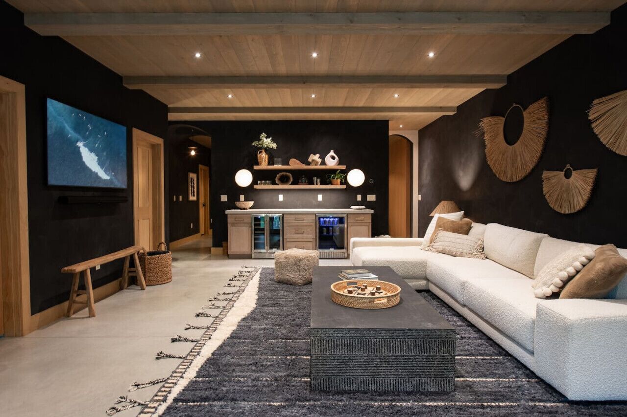 Uma sala de estar moderna com um sofá seccional, uma mesa de centro e uma TV fixada na parede.