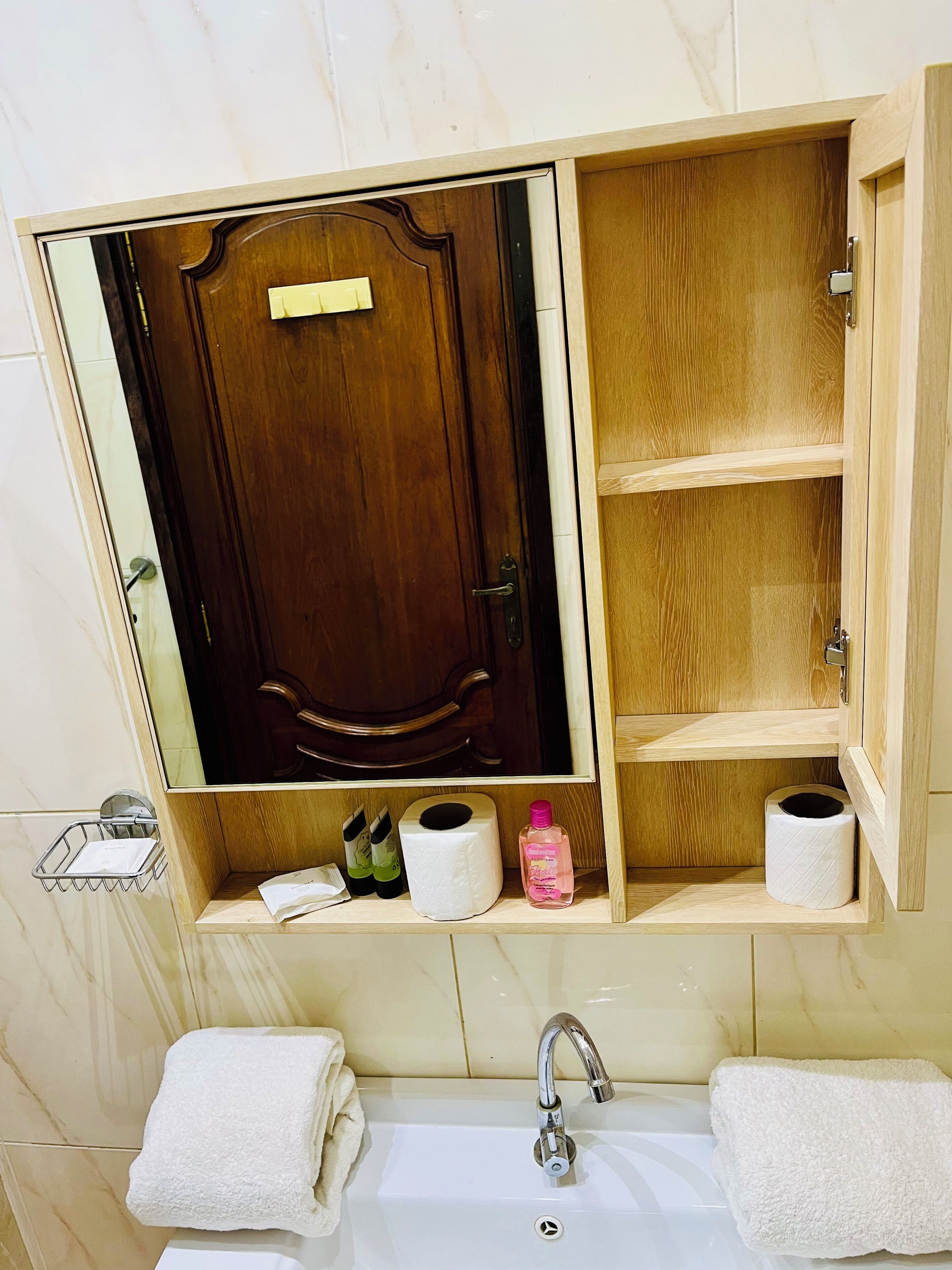 A bathroom with a wooden vanity, a mirror, a sink, and two towels.