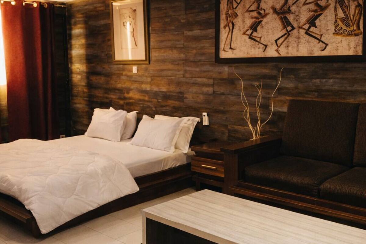 A modern bedroom with a bed, a sofa, a coffee table, and a wall with artwork.