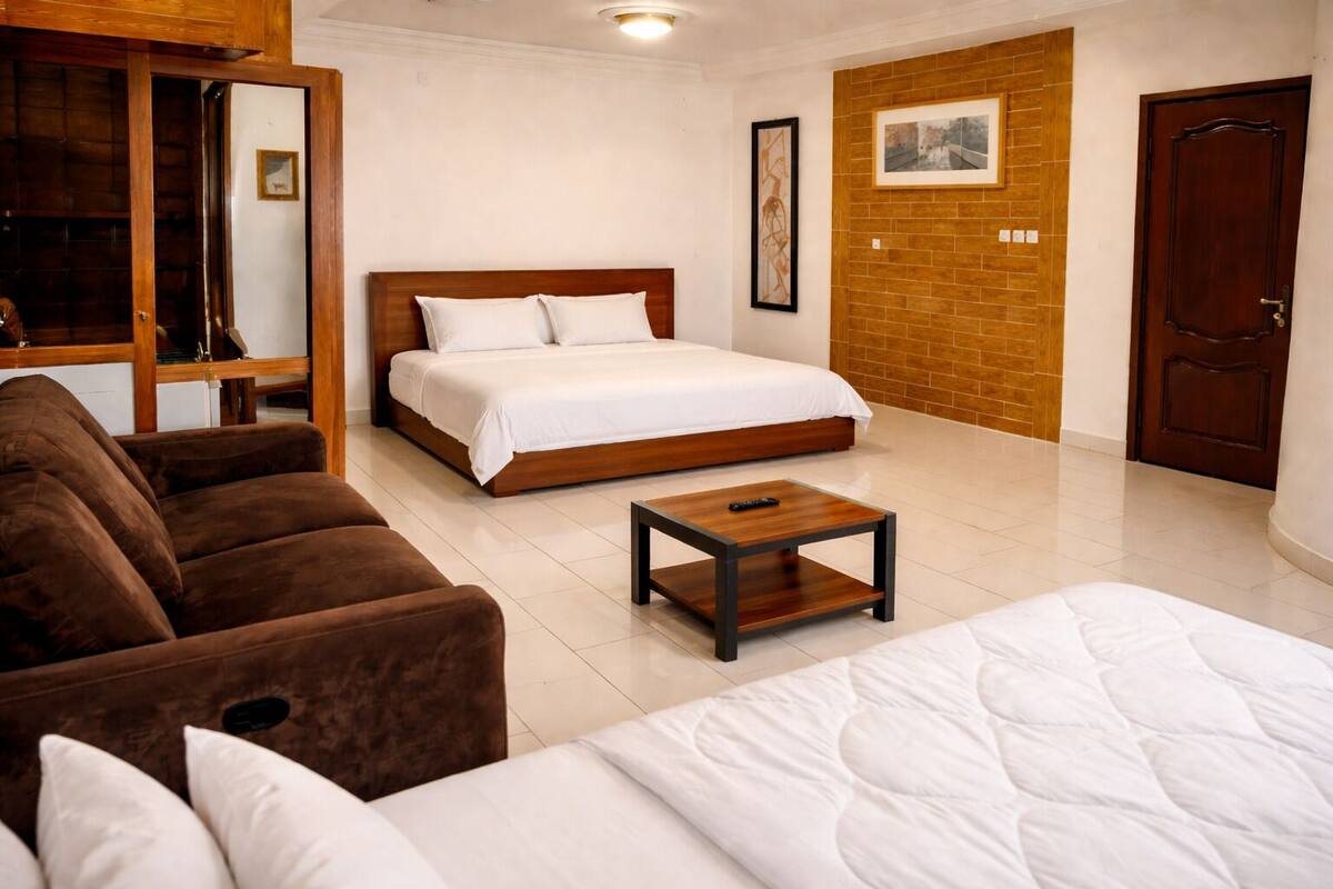 A hotel room with a bed, a sofa, a coffee table, and a wooden door.