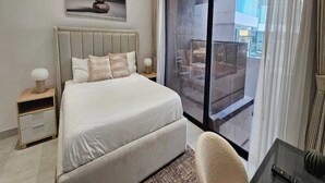 Moderni hotellihuone, jossa on suuri sänky, pieni työpöytä ja parveke, jolta on näkymä kaupunkiin.