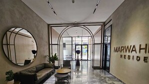 Moderni aula, jossa on kaareva peili, sohva, pyöreä pöytä ja kyltti, jossa lukee: ”MARWA HOTEL RESIDENCE”.