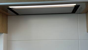 Eine moderne Küche mit weißen Schränken, einem eingebauten Backofen und einer Edelstahl-Dunstabzugshaube.