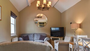 A cozy living room with a high ceiling, a large mirror, a flat-screen TV, and a dining area with chairs and a table. - Great ground floor apartment in the heart of Aberystwyth with shared hot tub. (Aberystwyth)