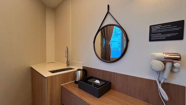 A hotel bathroom with a sink, mirror, and a hairdryer on the wall. - Hotel Regen (Seoul)