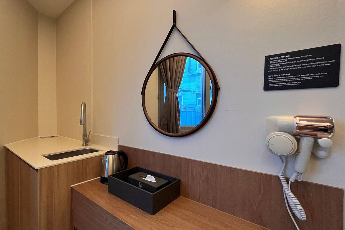 A hotel bathroom with a sink, mirror, and a hairdryer on the wall.