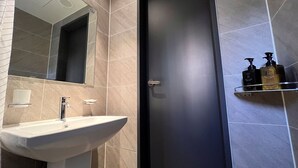 Un baño con lavamanos, espejo y artículos de aseo en un estante.