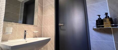 A bathroom with a sink, mirror, and toiletries on a shelf.