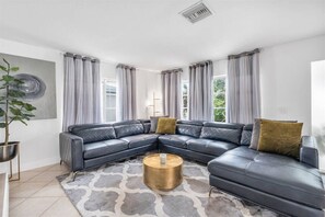 A modern living room with a sectional sofa, a round coffee table, and a potted plant.