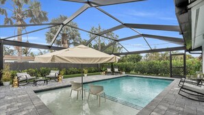 Et overdækket udendørs swimmingpool med liggestole og parasol.