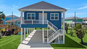A two-story house with a balcony and a covered porch. - Beachside Serenity | Modern, Near the Beach (Galveston)