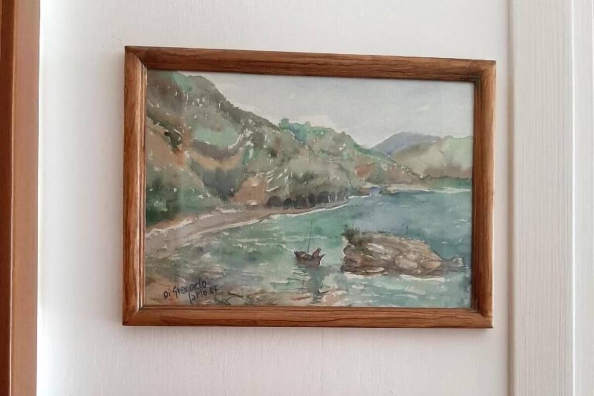 A framed painting of a coastal landscape with a wooden plaque below it that reads "Buondormire."