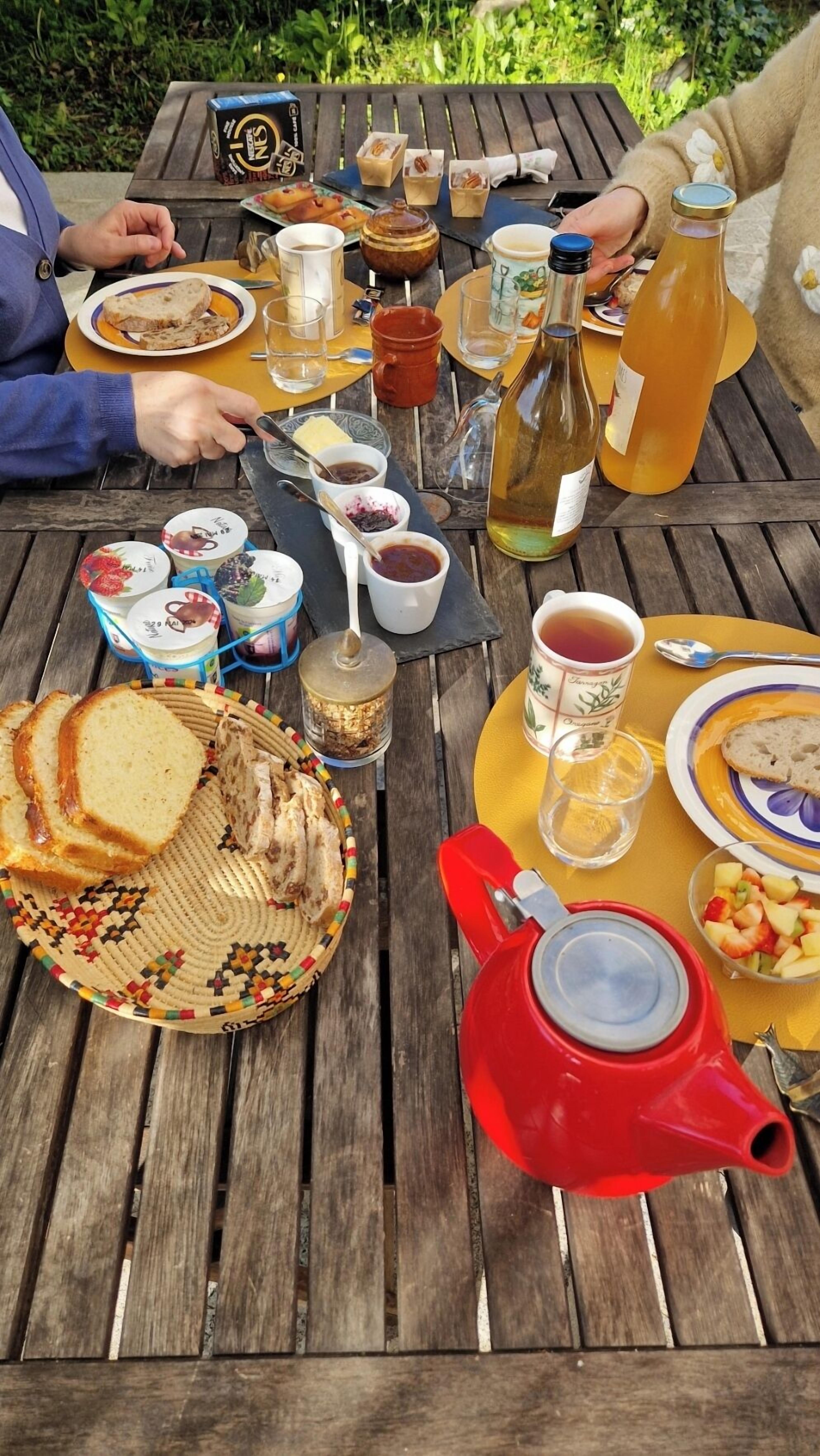 Una mesa de madera dispuesta con diversos alimentos, como pan, frutas y salsas, sugiriendo un picnic o comida al aire libre.